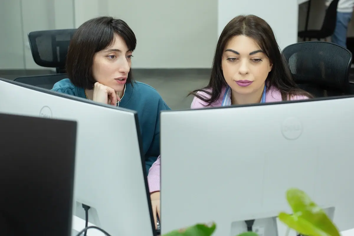 Two ARQA employees look at two screens and discuss design solutions.